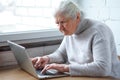 An old woman is sitting at the table in front of laptop Royalty Free Stock Photo