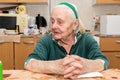 An old woman sitting by the table at the kitchen