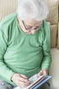 Old woman solving crossword puzzle at home Royalty Free Stock Photo