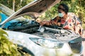 An old woman standing at a broken car trying to fix the car Senior woman the car is broken road and open the bonnet for check engi Royalty Free Stock Photo