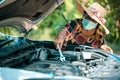 An old woman standing at a broken car trying to fix the car Senior woman the car is broken road and open the bonnet for check engi Royalty Free Stock Photo