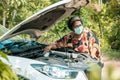 An old woman standing at a broken car trying to fix the car Senior woman the car is broken road and open the bonnet for check engi Royalty Free Stock Photo