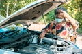 An old woman standing at a broken car trying to fix the car Senior woman the car is broken road and open the bonnet for check engi Royalty Free Stock Photo