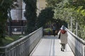 Old woman with a stick goes over the bridge