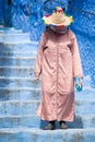 An old woman strolls through the streets of Chefchaouen, the blue town in Morocco, with her traditional costume