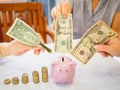 Old woman and two girls hands are putting bank note into pink piggy bank with golden coins graph, Saving money for future plan and Royalty Free Stock Photo