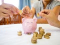 Old woman and two girls hands are putting golden cions into pink piggy bank, Saving money for future plan and retirement fund Royalty Free Stock Photo