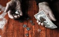 Old woman with very little money. Poverty concept. Pensioner with one dollar note and coins in hands. Economy and crisis in the Royalty Free Stock Photo