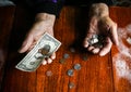 Old woman with very little money. Poverty concept. Pensioner with one dollar note and coins in hands. Economy and crisis in the Royalty Free Stock Photo