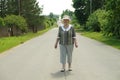 Old woman walking on the road at the sunny day Royalty Free Stock Photo