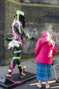 Old woman with walking stick admiring a Johnny Walker figurine at the Fringe Festival in Edinburgh