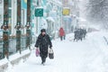 An old woman walks on a snowy street during a snowfall. A blizzard in the city. During a blizzard, an elderly woman walks along Royalty Free Stock Photo