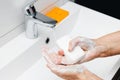 Old woman washing hands under streaming water from faucet with soap in bathroom, hygiene concept Royalty Free Stock Photo