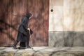 Old woman wearing a erbiantraditional back outfit walking alone in the streets of Sombor.