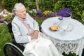 Old woman in a wheelchair drinking tea on the terrace Royalty Free Stock Photo