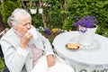 Old woman in a wheelchair drinking tea on the terrace Royalty Free Stock Photo