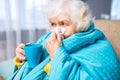 old woman wrapped on blue blanked at home feel sick runny nose