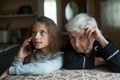 The old woman grandmother listens as the granddaughter of a little girl talking on a mobile phone. Family.