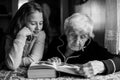 An old woman - a granny with a little girl - granddaughter reading a book. Royalty Free Stock Photo