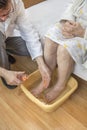 Old woman soaking feet in a bowl of water.
