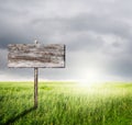 Old Wood sign with slope grass and rainclouds Royalty Free Stock Photo