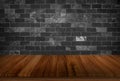 Old wood table with black stone concrete block wall in dark room background Royalty Free Stock Photo