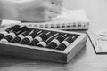 Old wooden abacus for counting money on a wooden table and a woman's hand writes in a notebook and money lies nearby Royalty Free Stock Photo