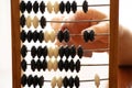 Old wooden abacus for counting money and a woman's hand on a bright light close-up