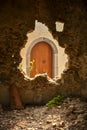 An old wooden arched door in Sicily seen through a broken hole i