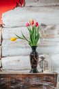 Old wooden background with tulips in vase and candlestick