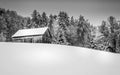 Old wooden barn on the hill covered with snow and forest in the background. Winter scenery in Vermont. Royalty Free Stock Photo