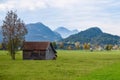 Old wooden barn in a meadow in the Alps in autumn with mountains Royalty Free Stock Photo