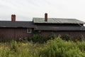 Old wooden barn - weathered texture - green metal roof - surrounded by wild grass and plants - cloudy sky backdrop Royalty Free Stock Photo