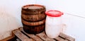 Old wooden barrel with metal rings and big white plastic container with red cap Royalty Free Stock Photo