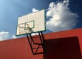 Old wooden basketball hoop on an orange cement wall with clear blue sky and clouds Royalty Free Stock Photo