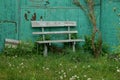 Old wooden bench in the green grass near the wall Royalty Free Stock Photo