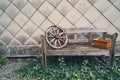 Old wooden bench with a wooden wagon wheel and a flower pot Royalty Free Stock Photo