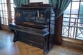 Old wooden black piano. Black piano stands against the wall . Old wooden black piano keys on wooden musical instrument Royalty Free Stock Photo