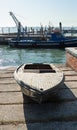 Old wooden boat on concrete slabs in the background of a blue fishing boat Royalty Free Stock Photo