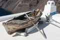 Old wooden boat resting on the white roof of Santorini