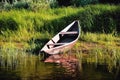 old wooden boat on the river bank against the background of green grass and bushes, reflections in the water Royalty Free Stock Photo