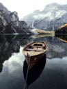 An old wooden boat stands near a boat station on a lake with a reflection of the mountains Royalty Free Stock Photo