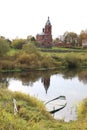 Stink blue wooden boat in the river coast among green grass and cane with church and cloudy sky reflection in calm water Royalty Free Stock Photo