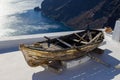 Old wooden boat on a top of a white building in Santorini with blue sea on its background Royalty Free Stock Photo