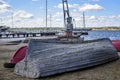 Old wooden boat is upside down on the river bank. Gray paint peels off the bottom and sides of the boat Royalty Free Stock Photo