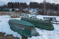 Old wooden boats lie in the snow on the shore of an ice-covered frozen lake in the winter. Royalty Free Stock Photo