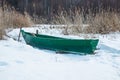 Old wooden boats lie in the snow on the shore of an ice-covered frozen lake in the winter. Royalty Free Stock Photo