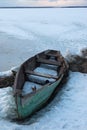 Old wooden boats lie in the snow on the shore of an ice-covered frozen lake in the winter. Royalty Free Stock Photo