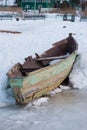 Old wooden boats lie in the snow on the shore of an ice-covered frozen lake in the winter. Royalty Free Stock Photo