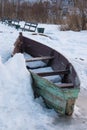 Old wooden boats lie in the snow on the shore of an ice-covered frozen lake in the winter. Royalty Free Stock Photo